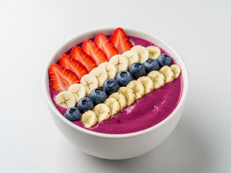 bol de smoothie bowl aux fruits rouges saupoudré de graines de chanvre décortiquées, cuillère en bois posée à côté, styl…