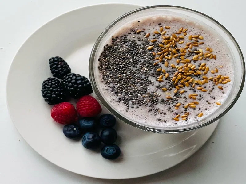 smoothie avec graines de lin saupoudrées, graines entières et moulues à côté